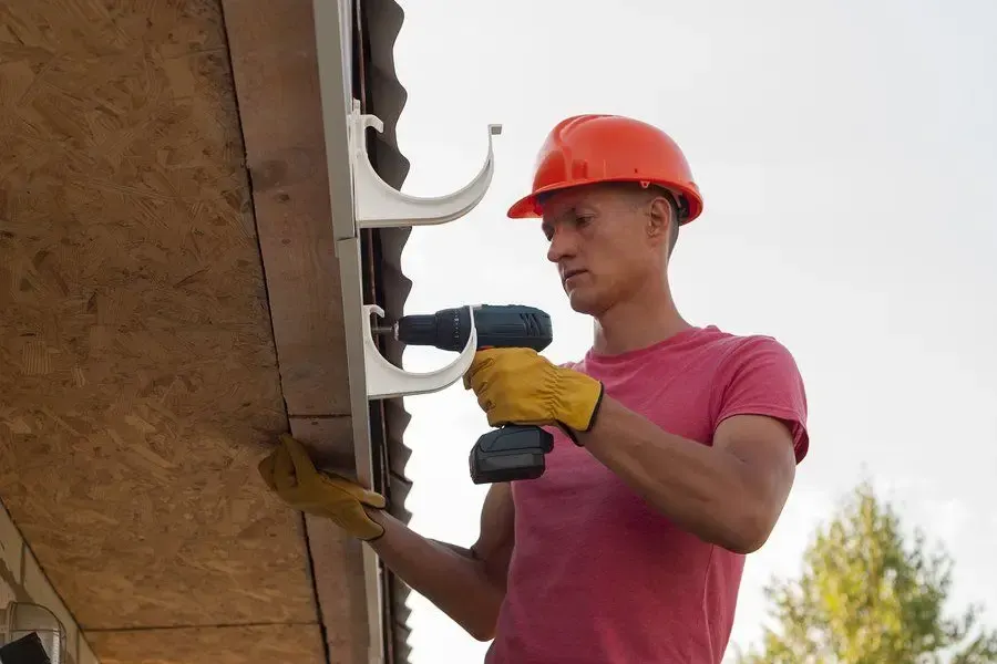 Inspecting a gutter connection beside a downspout