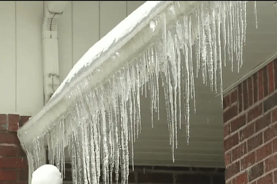 Ice and icicles gathered along a winter roof edge